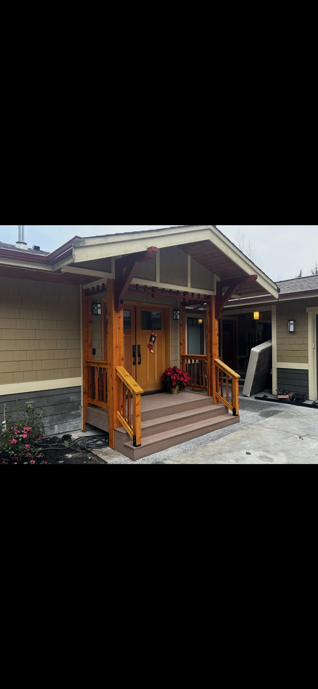 Modern timber-framed entry portico with composite deck and glass doors on residential home