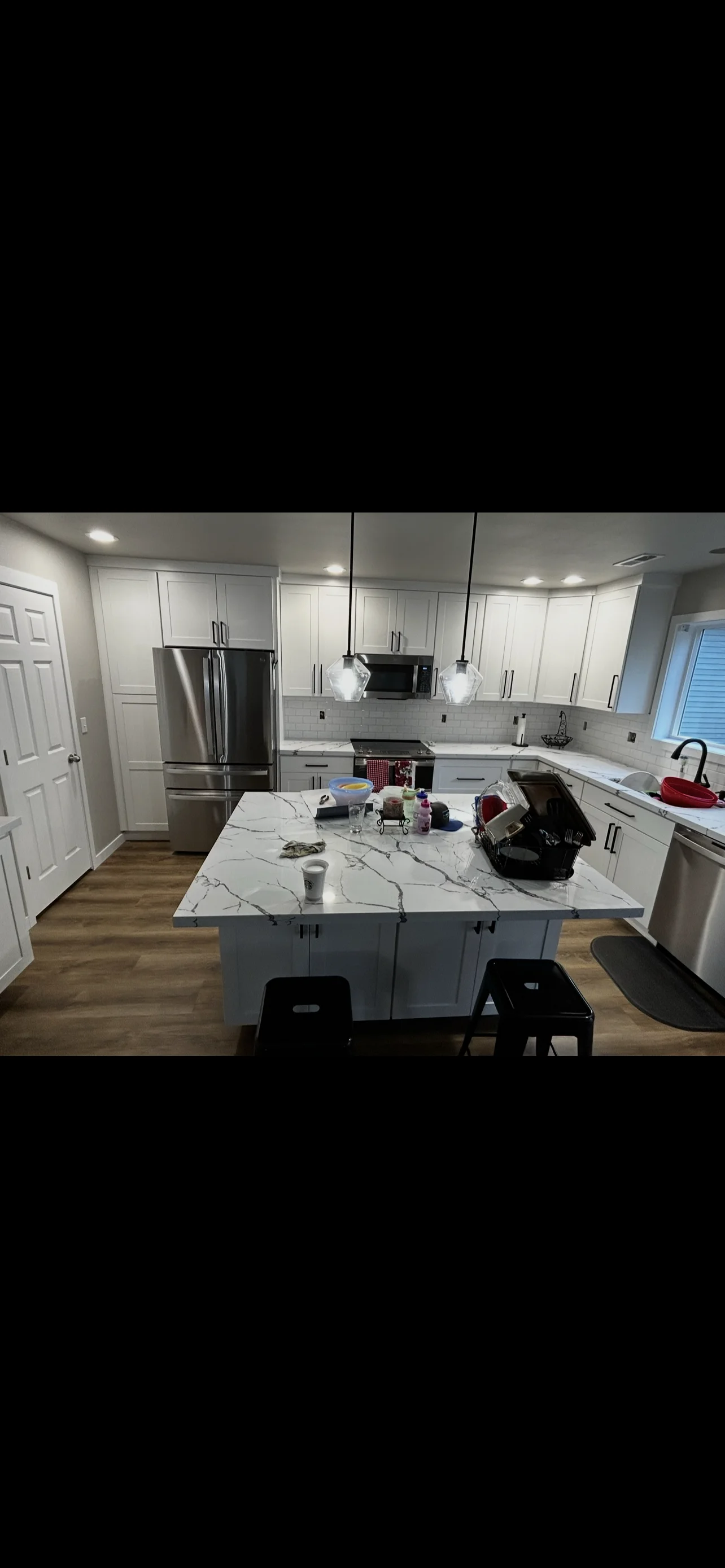 Modern kitchen with white cabinets, marble countertop island, and stainless steel appliances