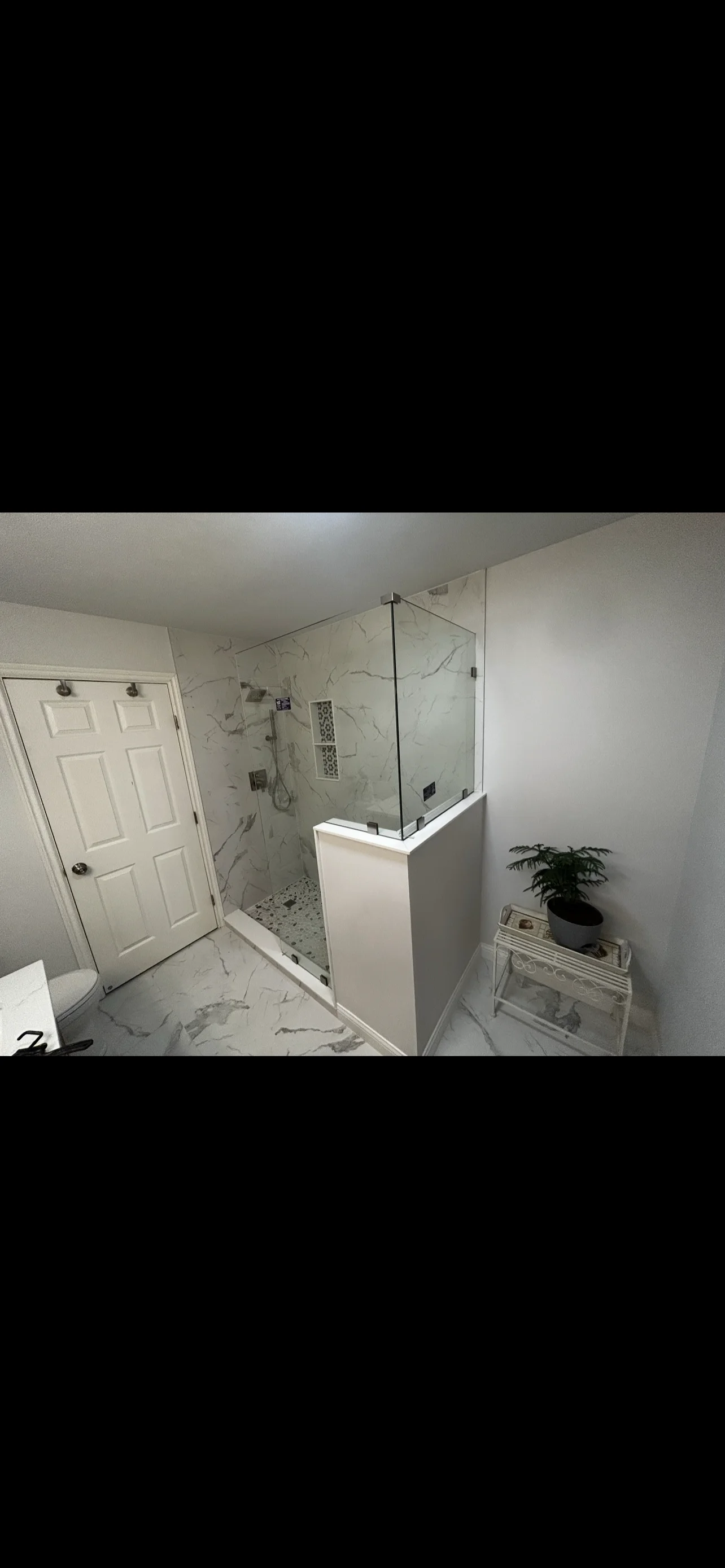 Modern bathroom with marble tile shower, frameless glass enclosure, and marble flooring
