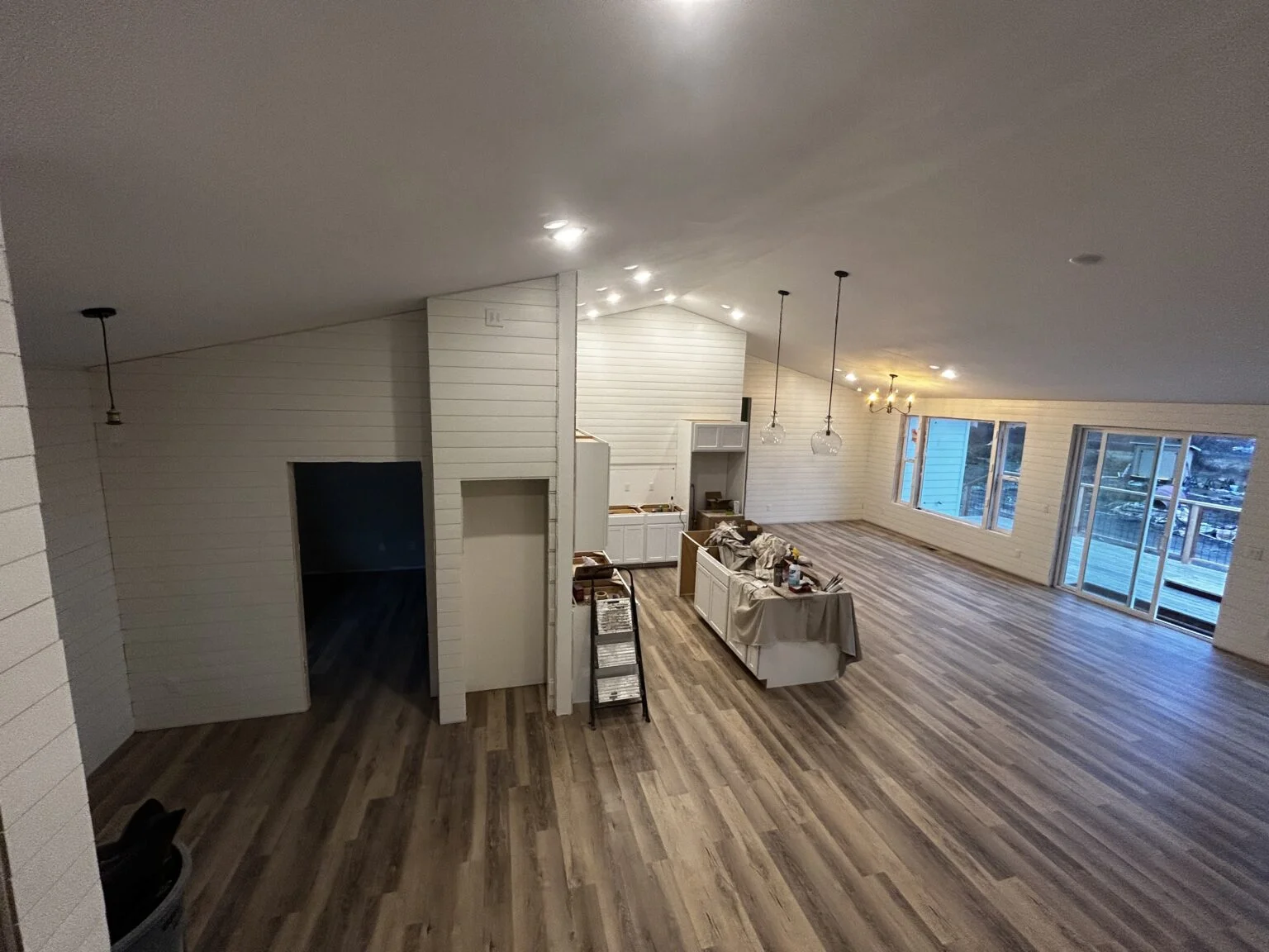 Modern interior with white shiplap walls, wood-look flooring, and pendant lighting fixtures