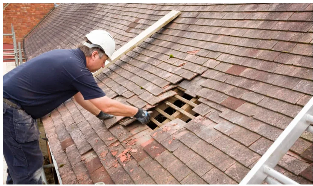 A residential roof in Oak Harbor, Washington showing a contractor repairing lifted shingles and resealing flashing along a roof valley. The home sits in a coastal setting typical of Whidbey Island.